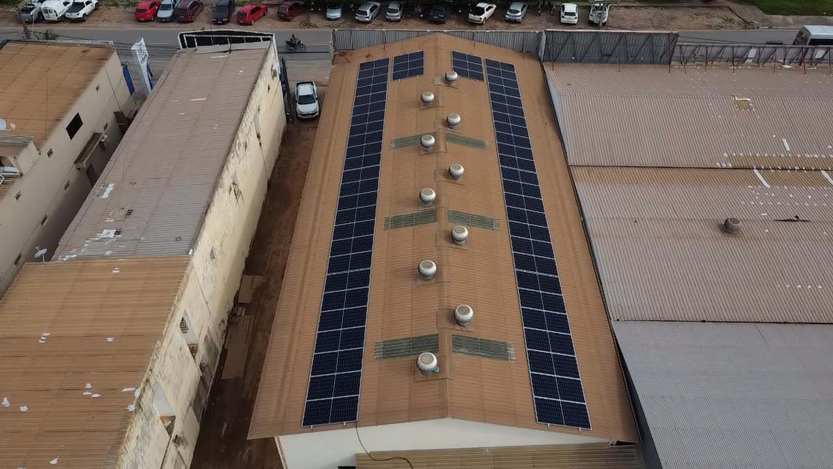 Vista aérea de galpão industrial com fileiras de painéis solares